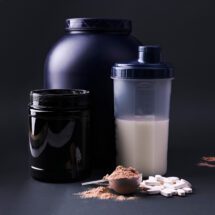 Sports nutrition supplements on a black background. Fitness, bodybuilding, healthy lifestyle concept. Whey protein powder in measuring scoop. Copy space